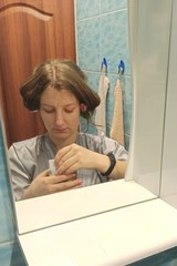 European woman hold face mask at bathroom