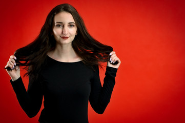 Naklejka premium Photo of a pretty young brunette woman with a smile with good makeup on a red background. Concept girl talking in front of the camera with emotions.
