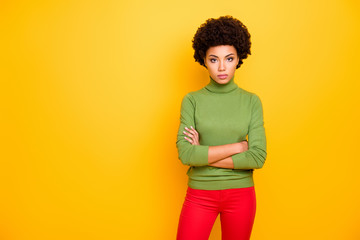 Photo of curly wavy serious confident woman with hands folded in red pants looking at you with clever eyes isolated vivid color background