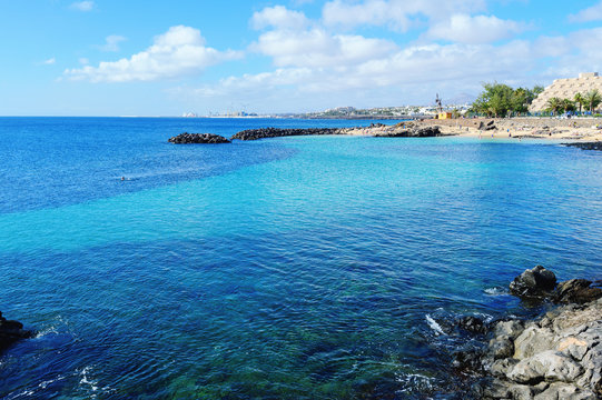 Lagoon with turquoise clear water in Playa Jablillo beach, in Costa Teguise, Lanzarote, Canary islands. Sandy beach with blue sea, volcanic rocks