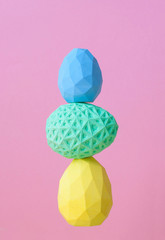 Polygon pattern Easter eggs standing on top of each other on pink background