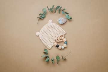 Wooden teether and baby hat on beige background