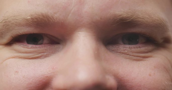 Close up brown eyes of serious man staring and frowning. Macro portrait of caucasian male face seriously looking into camera with negative emotion. Facial expression of confident man
