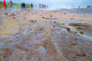 People watching boiling water in geothermal hot springs national park on Iceland