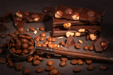 Pieces of chocolate with a nuts  lying on a dark texture table.
