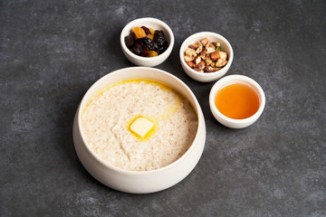 Oatmeal porridge with raisins, honey and nuts in a bowl