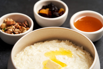 Rice porridge with milk, raisins, honey and nuts in a bowl.