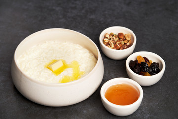 Rice porridge with milk, raisins, honey and nuts in a bowl.