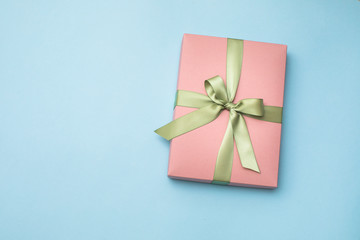 Obraz na płótnie Canvas Pink gift box with ribbon and bow on blue background