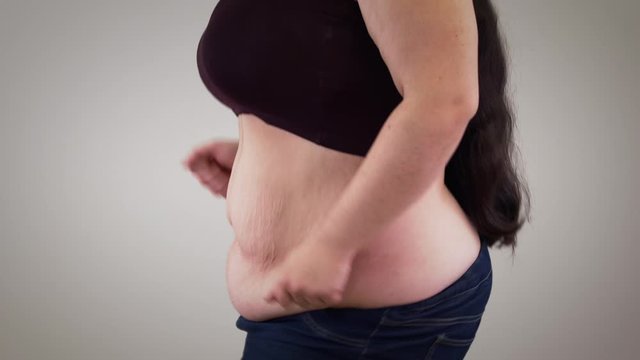 Close-up tummy of unrecognizable fat Caucasian woman dancing. Obese positive girl having fun. Overweight, obesity, lifestyle.