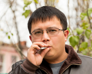 Closeup of a handsome young man smoking a cigarette outdoors