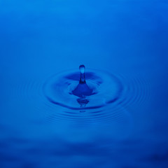 Splash from a drop of water on a blue background, close-up. Selective focus.