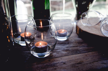 Candles on a wood table with glasses and wine