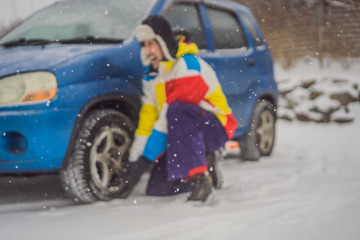 Winter accident on the road. A man changes a wheel during a snowfall. Winter problems