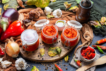 Colorful tabletop scene with raw ajvar surrounded with vegetables. Vegan chutney flat lay scene. Healthy eating