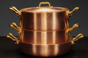 Set of copper cookware over dark background