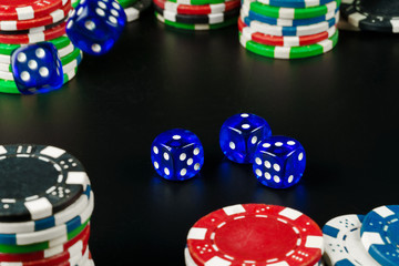 Dice and chips on black table close up