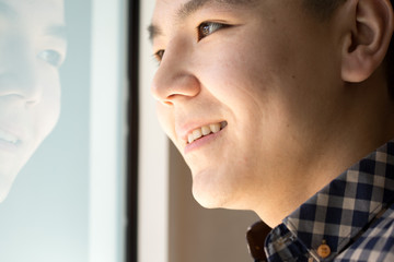 young man standing in front of the window and looks at street