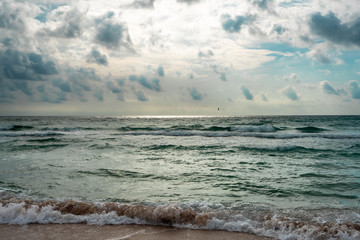 Fototapeta premium Beautiful Stormy Waves on the coast. Dramatic sky background. Sand beach. Amazing view of grey rainy clouds in the ocean. Sunny rays through the clouds on the horizon. 