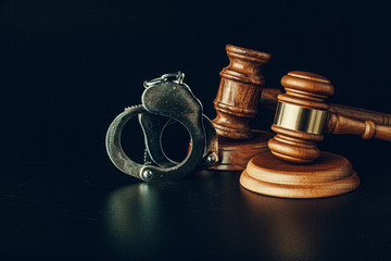 Judge gavel and handcuffs on dark black background