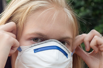 Blond girl wearing P2 N95 protection respiratory mask to reduce amount of breathing PM2.5 particles