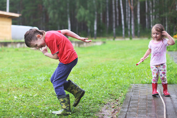 brother and sister play in rainy weather Children jump in puddle and mud in the rain.