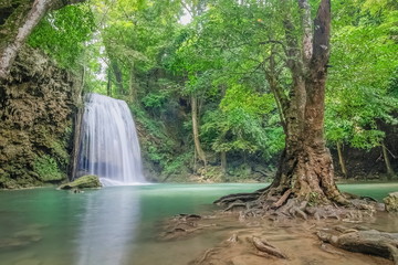 Beautiful silky water flowing on cliff rock around with blue-green water and green forest background, Erawan waterfalls 3th step, Kanchanaburi, west of Thailand.