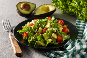 Salad with avocado, lettuce, tomato and flax seeds on gray background	