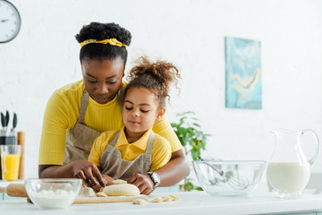african american mother near adorable kid sculpting dumplings in kitchen