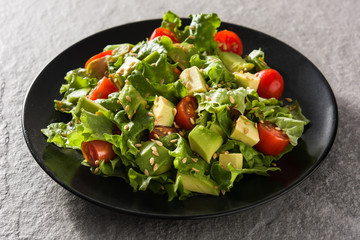 Salad with avocado, lettuce, tomato and flax seeds on gray background	