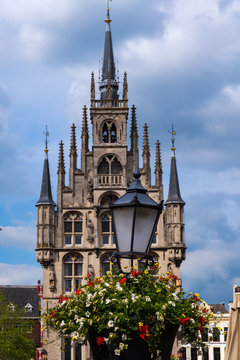 Eine mit Blumen geschmückte Laterne und das Rathaus von Gouda/NL im Hintergrund