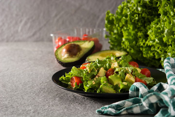 Salad with avocado, lettuce, tomato and flax seeds on gray background. Copy space	