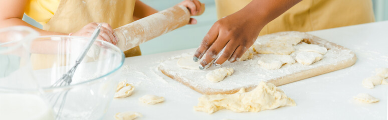 panoramic shot of african american kid holding rolling pin near mother and raw dumplings