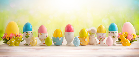 Easter concept with colorful decorated eggs in egg cups and flowers