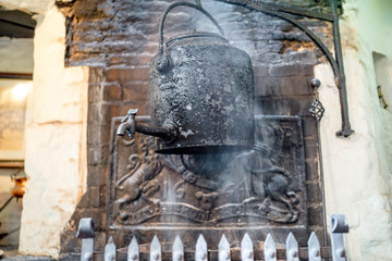 Fototapeta na wymiar Vintage kettle in the smoke of fireplace in old British pub