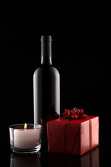 Gift box, bottle of wine, candle on black background.