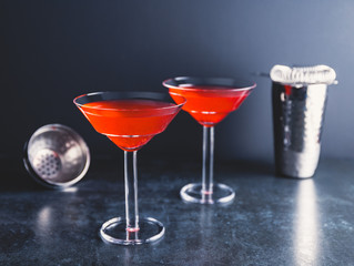 Red cocktail with lime in Martini glass on a table.
