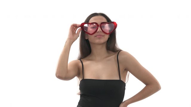 Young cheerful woman wearing heart shaped glasses and sending air kisses. Girl posing to camera in flirting manner