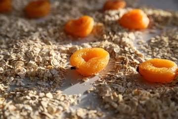 Healthy breakfast concept – oat flakes and dried apricot at sunny day. Food for heart health and energy. Creative granola or muesli ingredients