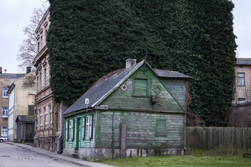 Fototapeta premium Old green wood house near weird green grass grown wall.