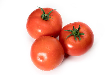 three fresh tomatoes with green leaves isolated on white background