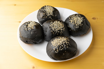 Loaf of charcoal bread bun with white sesame on top in the white plate