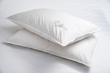 Two white pillows with feathers on the bed