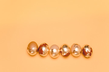 Easter greeting card. Golden eggs lined up in a row on a beige background