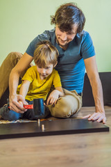 Fototapeta premium Father and son assembling furniture. Boy helping his dad at home. Happy Family concept