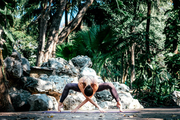 Be In the Moment. Full-length shot of caucasian woman standing in Spider pose, while practicing yoga outdoors, in a garden. Healthy lifestyle and relaxation concept