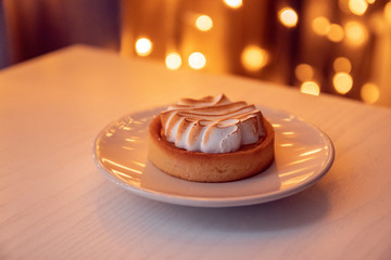 Fresh cake with airy cream on a white ceramic plate.