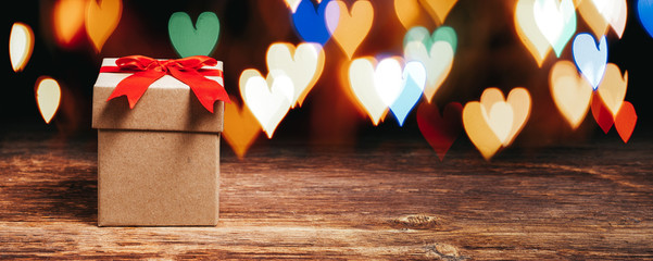  gift box on wooden table with shiny heart shaped lights.