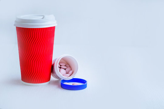 Red paper cup of coffee and pills on white-blue background. Place for text. Morning coffee and vitamins to cheer up. A healthy start to the day. Spring vitamin deficiency.