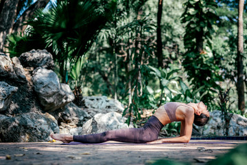 Exploring the yoga of life. Full-length shot of caucasian woman sitting in Fish pose, Matsyasana while practicing yoga outdoors, in a garden. Healthy lifestyle and relaxation concept